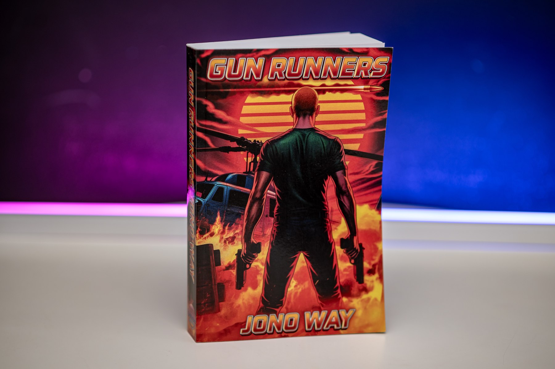 Gun Runners paperback standing against a Miami neon backdrop